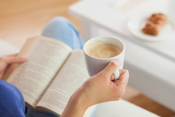 mom drinking coffee and reading aloud a chapter book to her kids