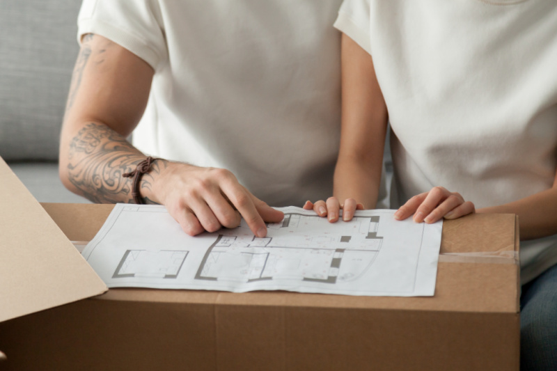 husband and wife studying floor plan spread out on top of cardboard box