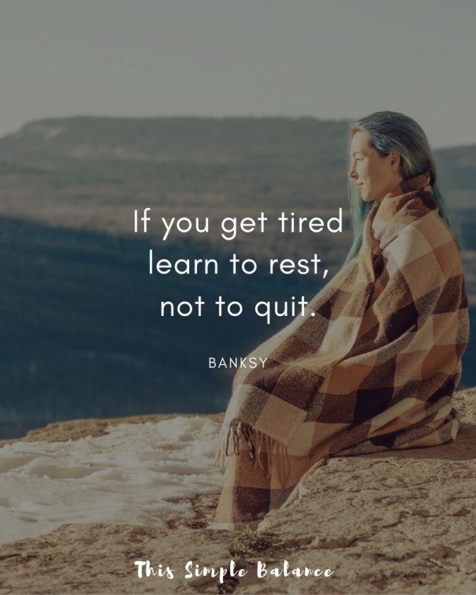 woman sitting on rock on mountaintop with brown checkered blanket wrapped around her, with text overlay, "If you get tired learn to rest, not to quit. Banksy"