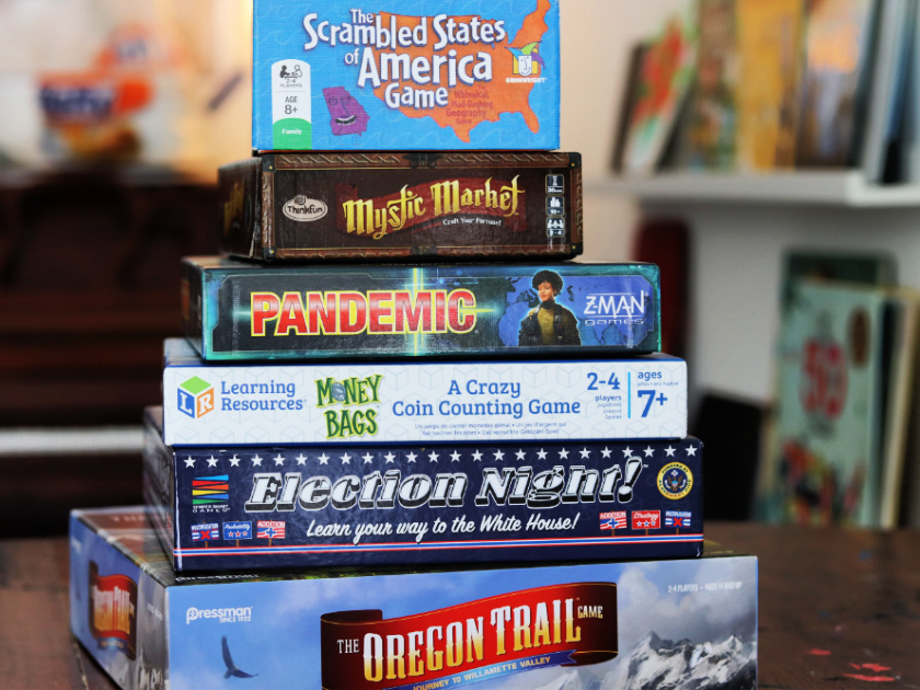 stack of favorite educational board games on table, including oregon trail and scrambled states of america