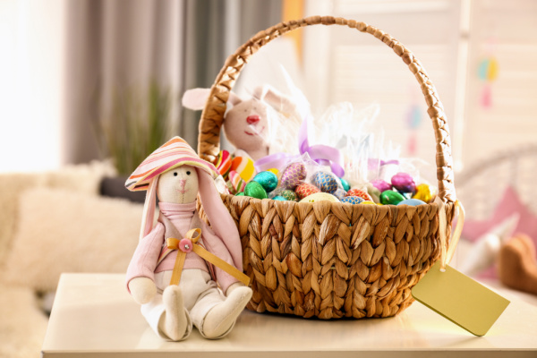 Easter basket for kids with chocolate eggs and a bunny stuffed animal sitting next to it