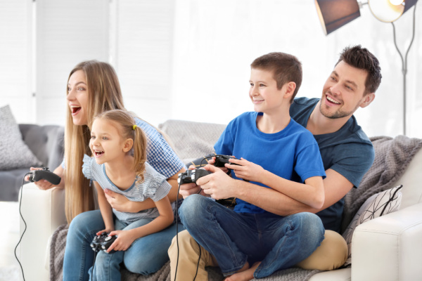 mom and dad playing video games with two kids, all sitting together on couch