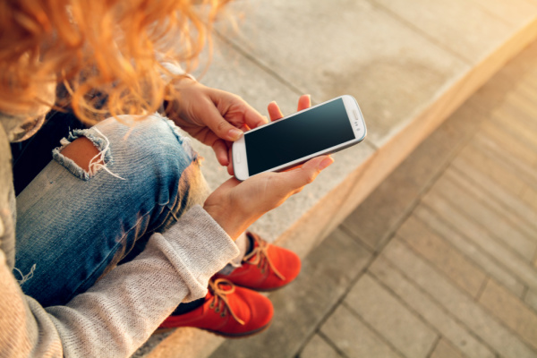 mom holding iphone on her hands, sitting outside