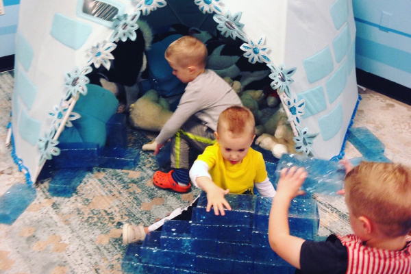 children visiting science museum, playing in igloo and building with pretend ice bricks