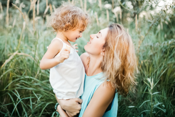 homeschool mom holding toddler in the middle of a field with tall grasses