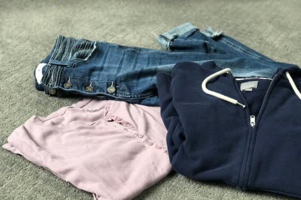 blue sweater, purple henley shirt, jeans laid out together on gray carpet