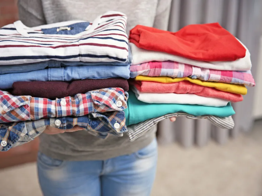 Woman holding stacks of folded clothes, closeup