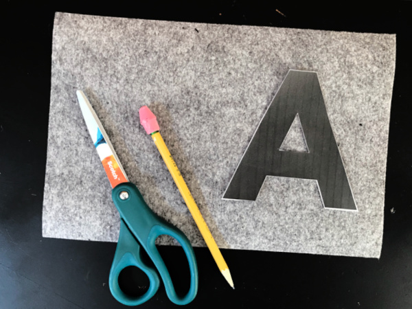 black cut out letter "A" on gray felt rectangle with pencil and scissors