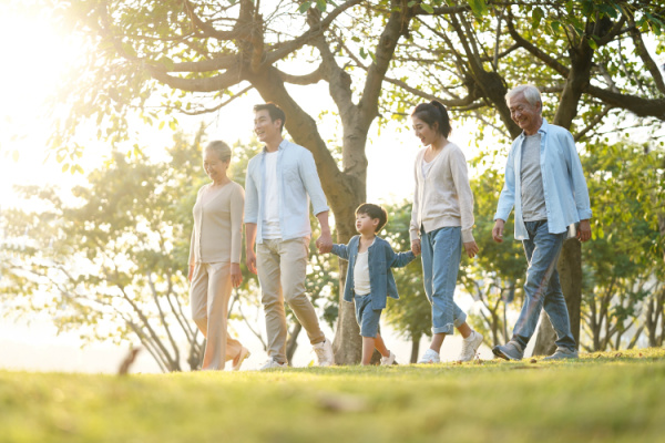 three generation happy asian family walking outdoors in park