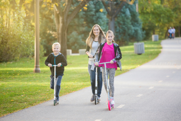 two kids and mom riding scooters together