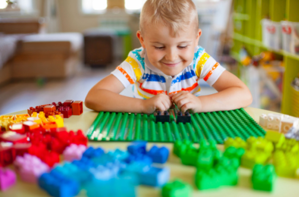 little boy playing with colorful duplo blocks