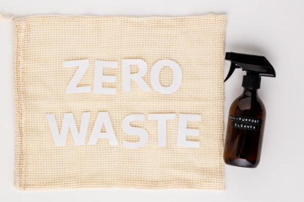 amber spray bottle next to mesh bag with white words "ZERO WASTE"