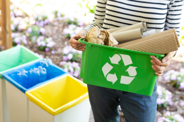 woman holding green recycling bin full of cardboard