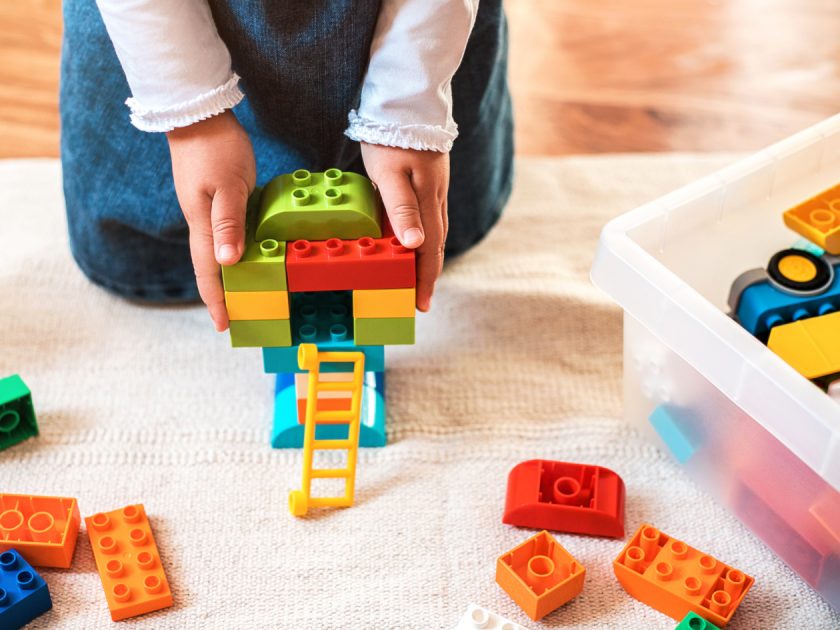 Little girl playing with her colorful blocks on the floor at home.