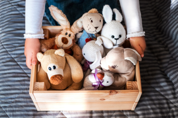 child cleaning up stuffed animals in wooden crate
