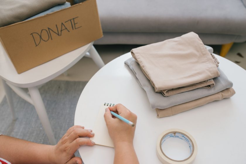 homeschool mom working on decluttering, sitting at table with list and donation box