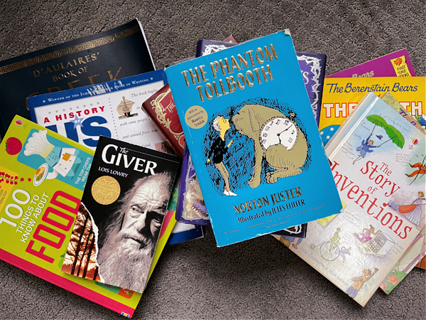 books for homeschool year on carpet, including The Phantom Tollbooth, The Giver, and The Story of Inventions