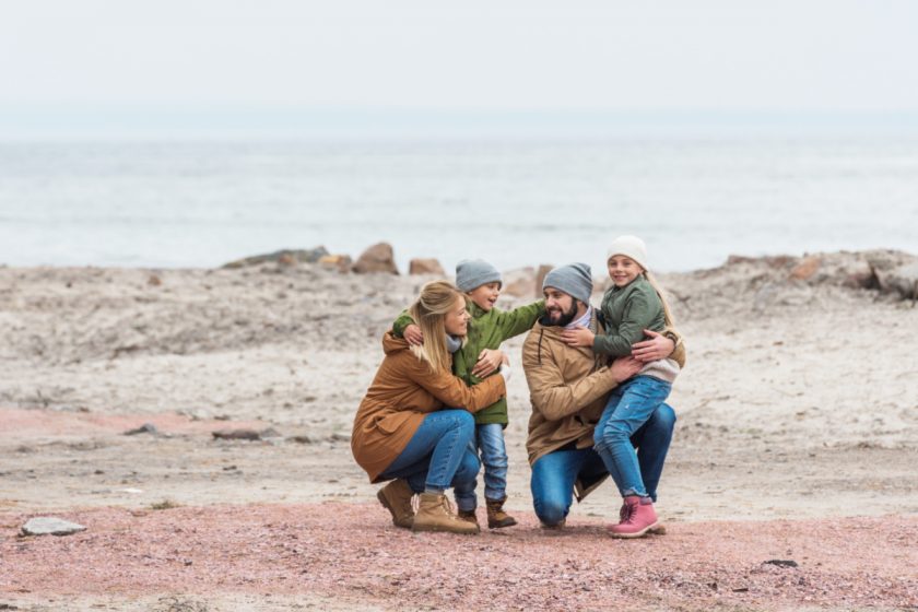 happy homeschool family of four at the beach together in winter
