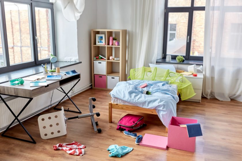 messy kids bedroom with toys and clothes strewn around the room