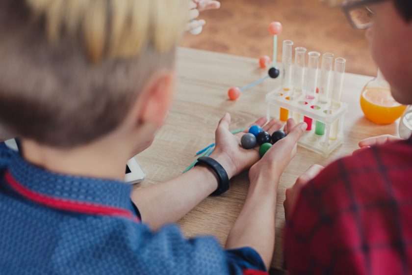 two boys doing STEM experiment with small balls and test tubes on desk