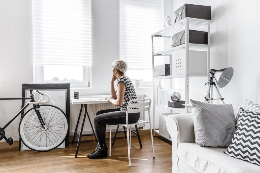 woman sitting at desk in black and white room contemplating the cons of minimalism