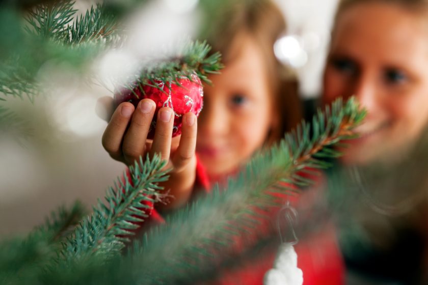 mom and daughter decoration christmas tree with red ball ornament in focus