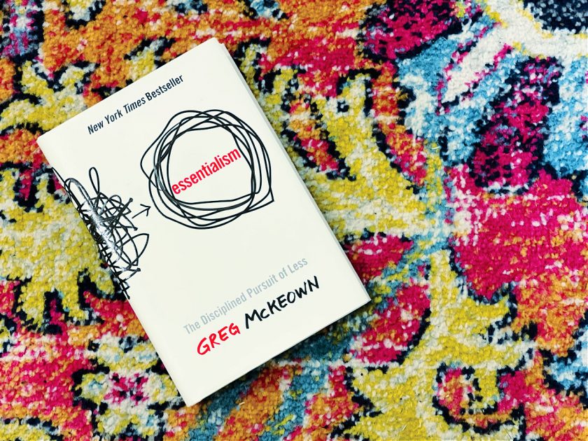 essentialism by greg mckeown black and white book cover on colorful patterned rug