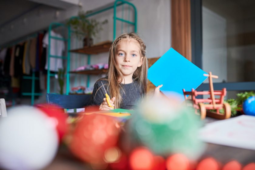 girl cutting paper and making christmas decorations at a table