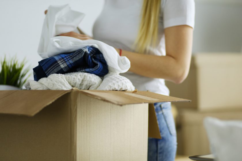 young woman decluttering and putting clothes in cardboard box
