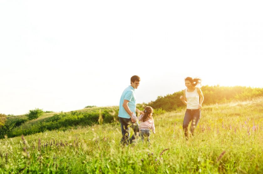 happy minimalist family enjoying extra time playing in a field together