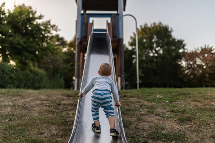 toddler boy climbing up slide