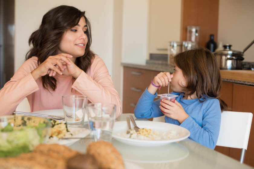 mother and daughter having dinner in kitchen