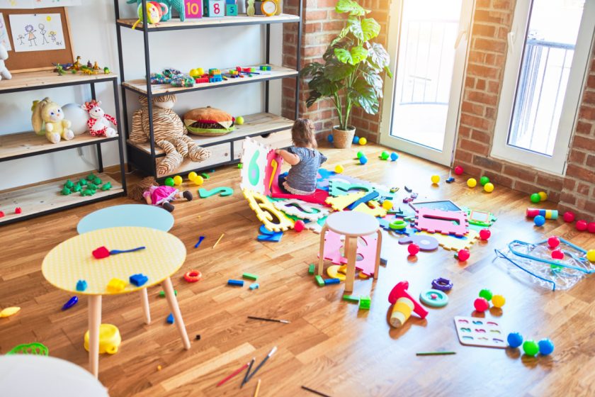 Toddler sitting on the floor surrounded by toys