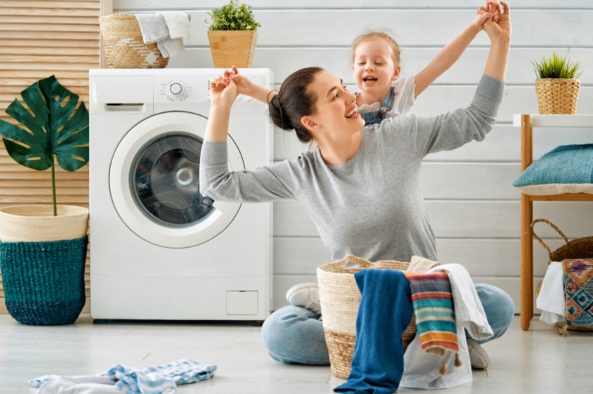 mom and daughter playfully doing laundry together