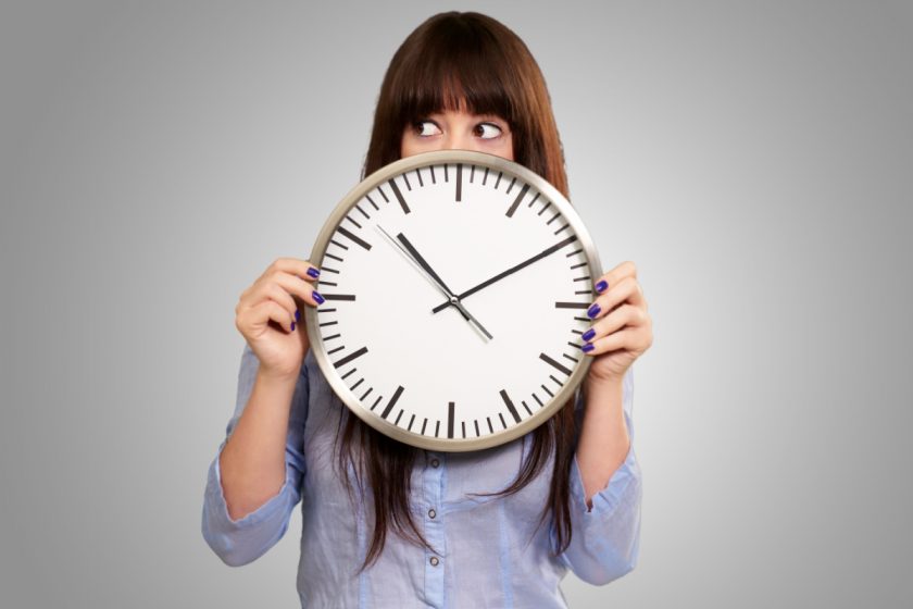 A Young Girl Holding A Clock On Gray Background