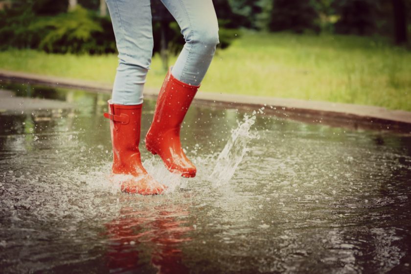 woman in red rainboots splashing in puddle