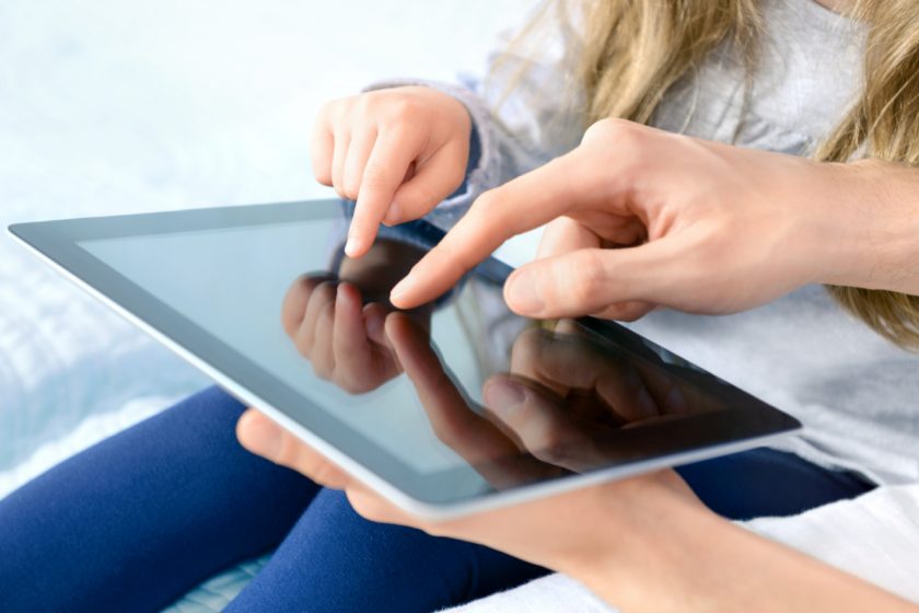 unschooling father with daughter playing on digital tablet. Selective focus on the child's finger.