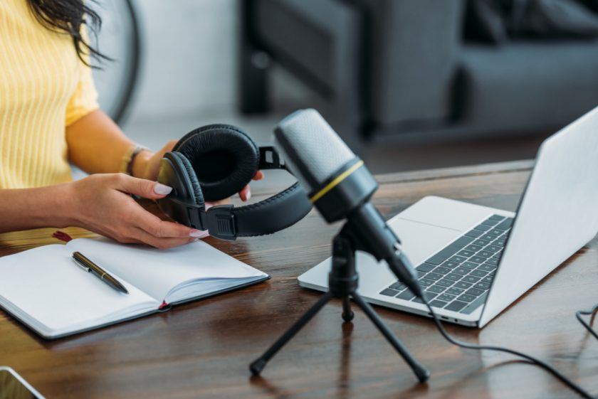 unschooling podcaster preparing to record, at desk with microphone, headphones and laptop