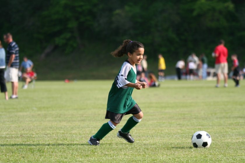 A young unschooled girl playing in a soccer league