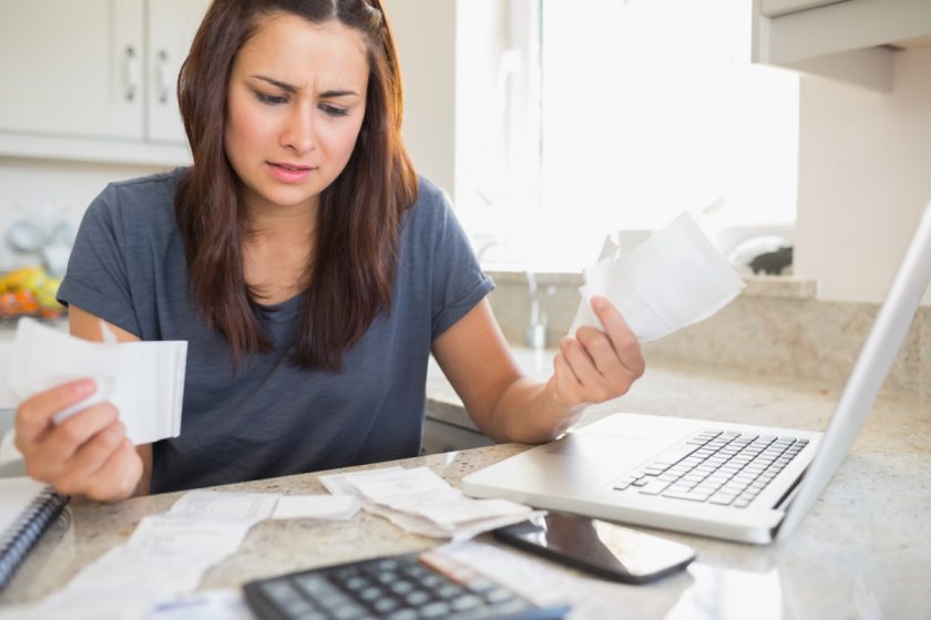 mom getting stressed over the cost of homeschooling while paying bills in the kitchen