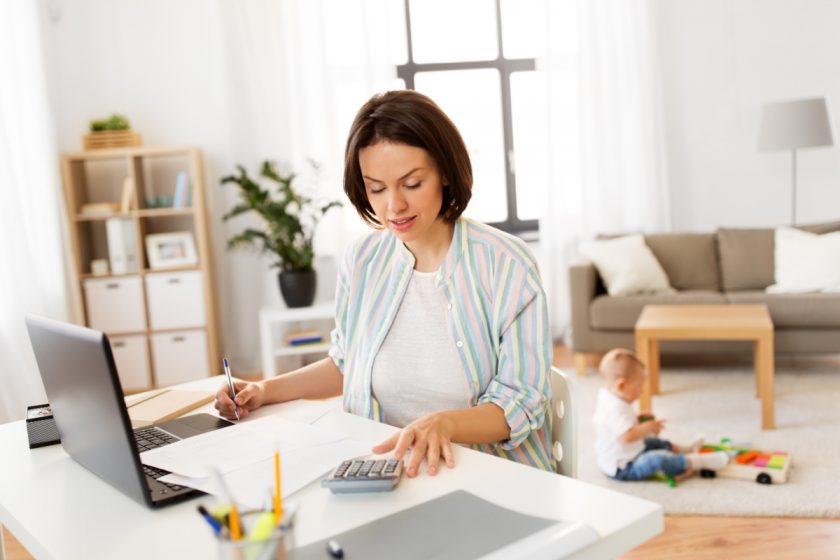 mom looking at the costs of unschooling while small child plays in background