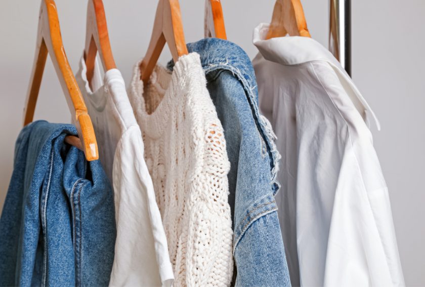 white and jean clothing pieces on hangers on rack