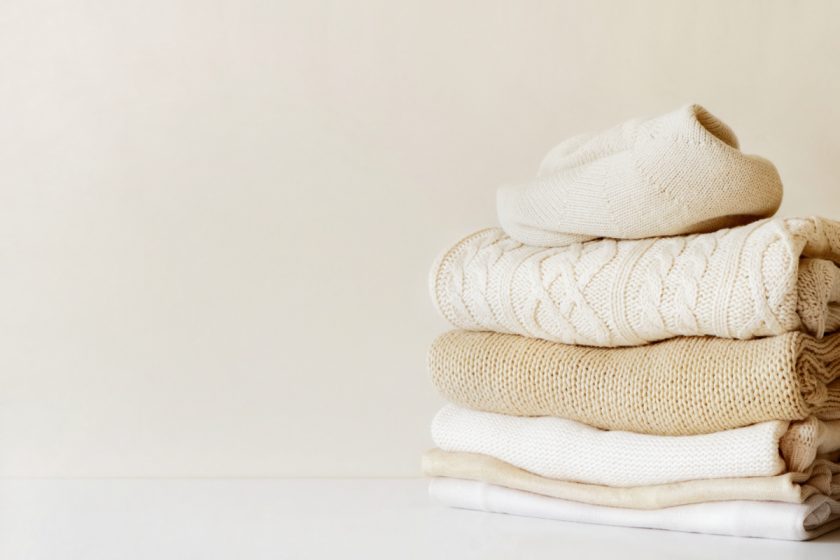 A stack of warm beige knit sweaters. The concept of winter personal uniform.