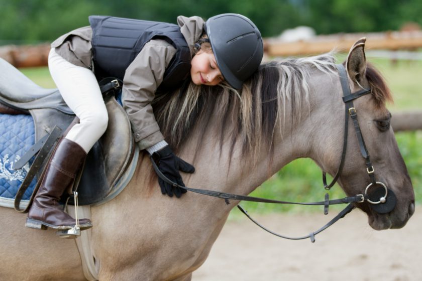 unschooled girl hugging horse during horseback riding lessons