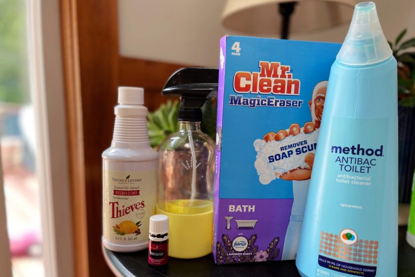 minimalist cleaning products on table - Thieves, glass spray bottle, magic erasers, method toilet cleaner