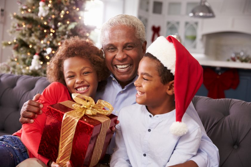 grandfather hugging smiling grandkids who gave him a gift at Christmastime