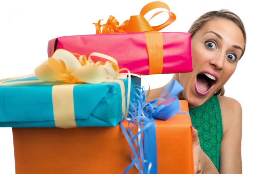 surprised work from home mom holding a pile of wrapped gifts