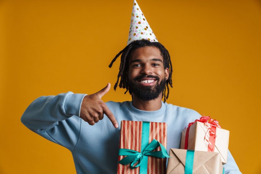 smiling minimalist man holding three birthday gifts