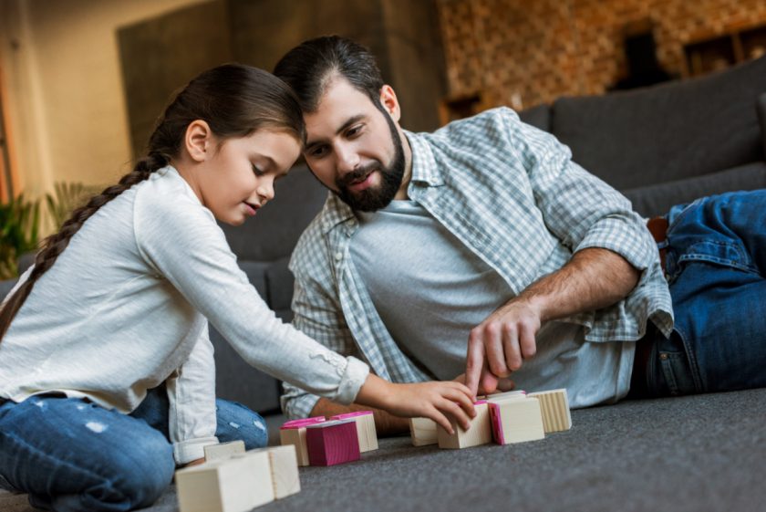 father playing with blocks on the floor with his daughter