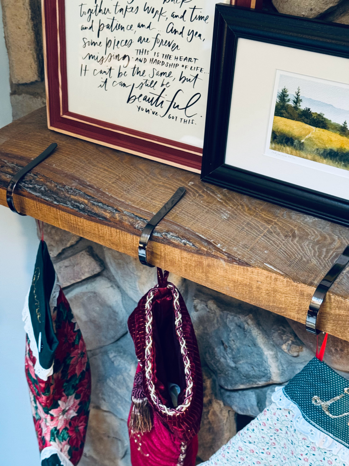 Minimalist Christmas stockings hanging on mantel with colorful art in background.